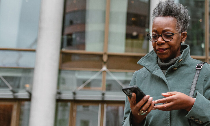 A woman on a smartphone in front of a sleek office building