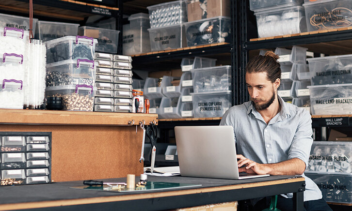 small business owner does inventory on his laptop