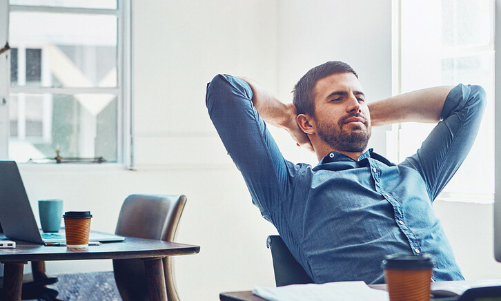 An employee leans back at his desk