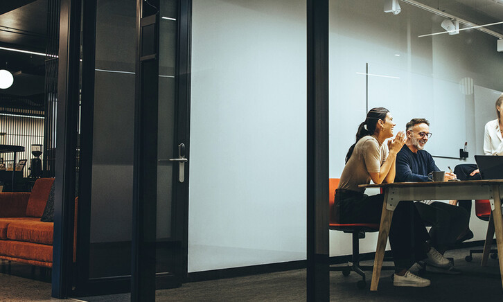 A group of employees gather in a meeting room
