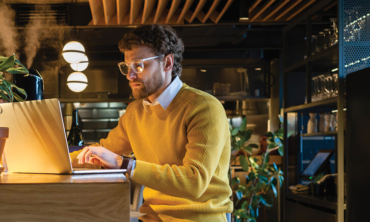 Businessman using laptop while sitting on seat at counter in cafe