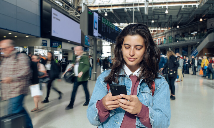 Woman looking at phone at a train station 