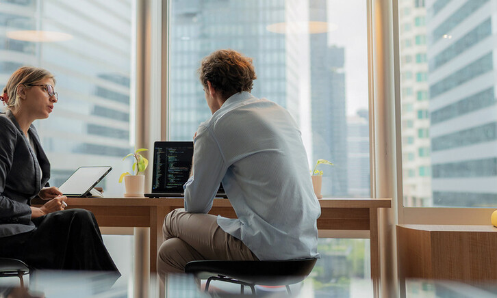 Adviser in modern office working on computer while speaking with clients