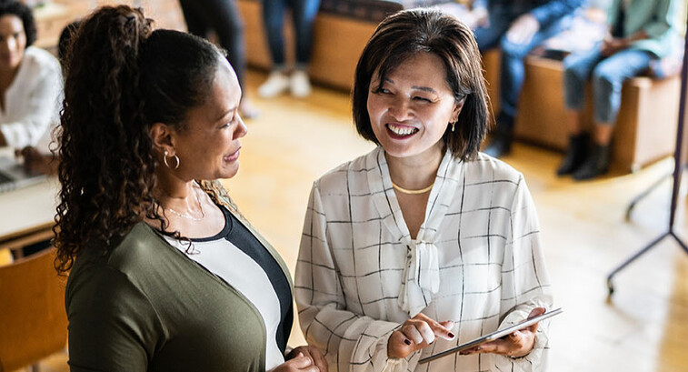 Two colleagues talking and using a digital tablet at work