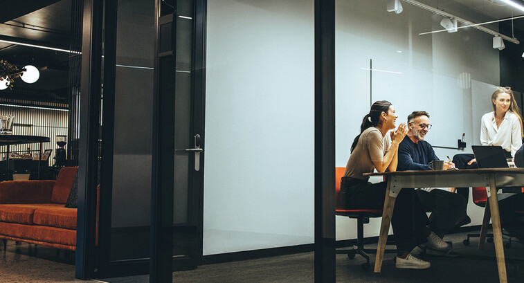 A group of employees gather in a meeting room