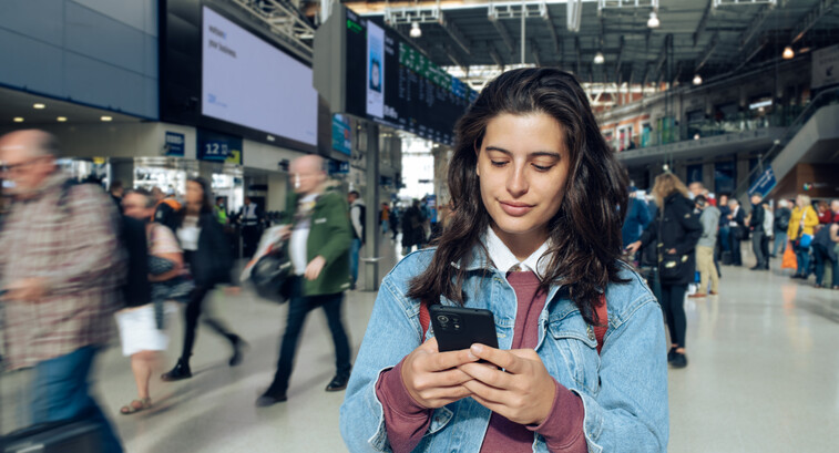 Woman looking at phone at a train station 