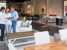 Couple shopping in a retail furniture store being helped by an associate with a tablet