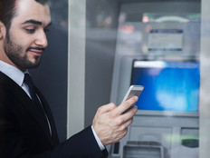 Man using smartphone by bank ATM 