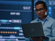 IT leader with laptop in room full of data visualizations 