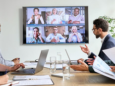 Diverse employees on online conference video call on tv screen in meeting room.