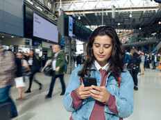 Woman looking at phone at a train station 