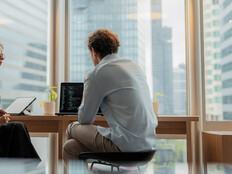 Adviser in modern office working on computer while speaking with clients