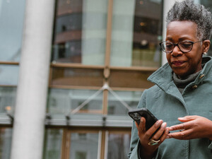A woman on a smartphone in front of a sleek office building