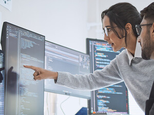 two people look at computer monitors