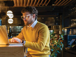 Businessman using laptop while sitting on seat at counter in cafe
