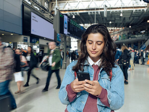 Woman looking at phone at a train station 