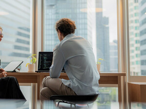 Adviser in modern office working on computer while speaking with clients