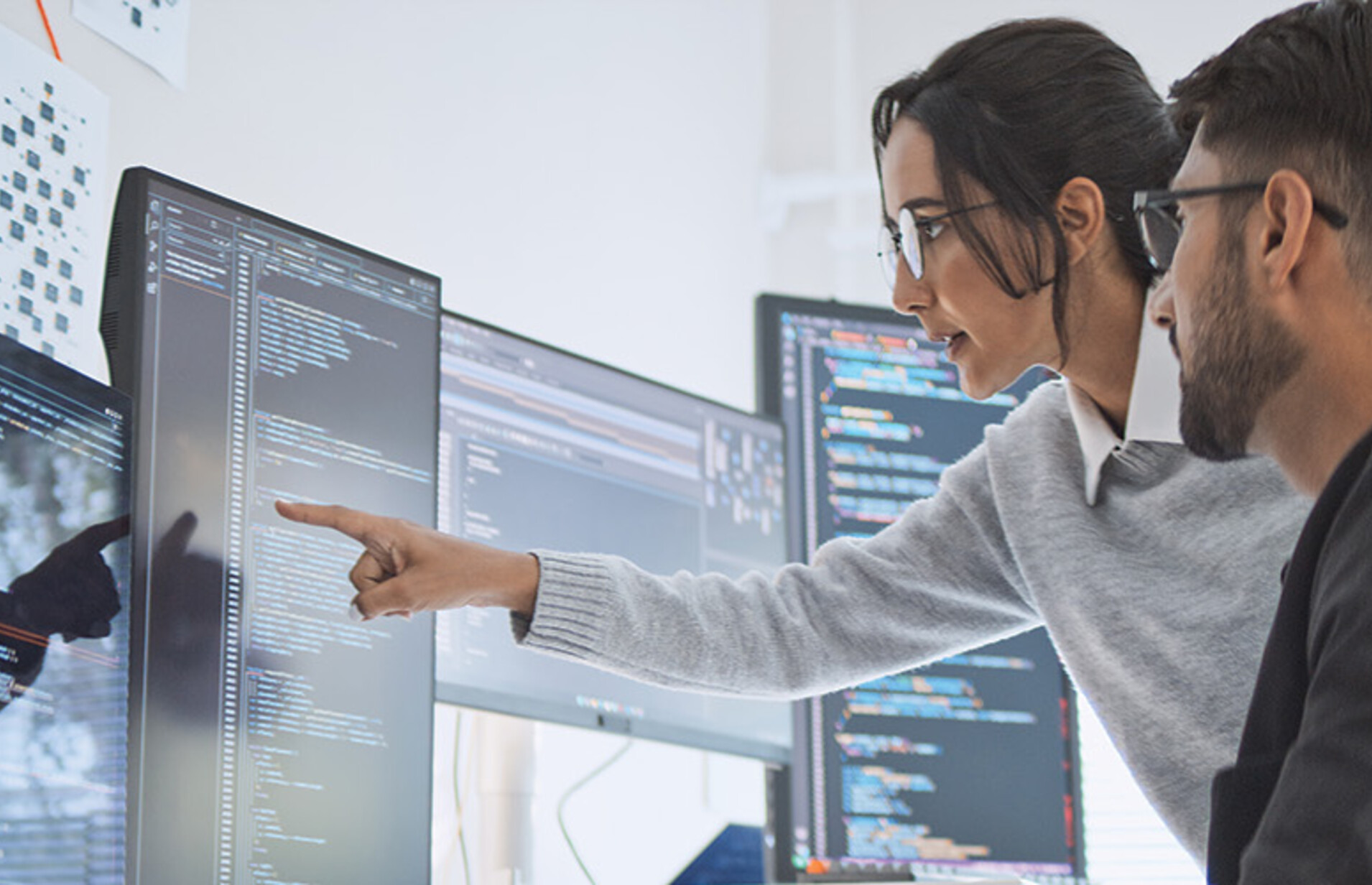 two people look at computer monitors