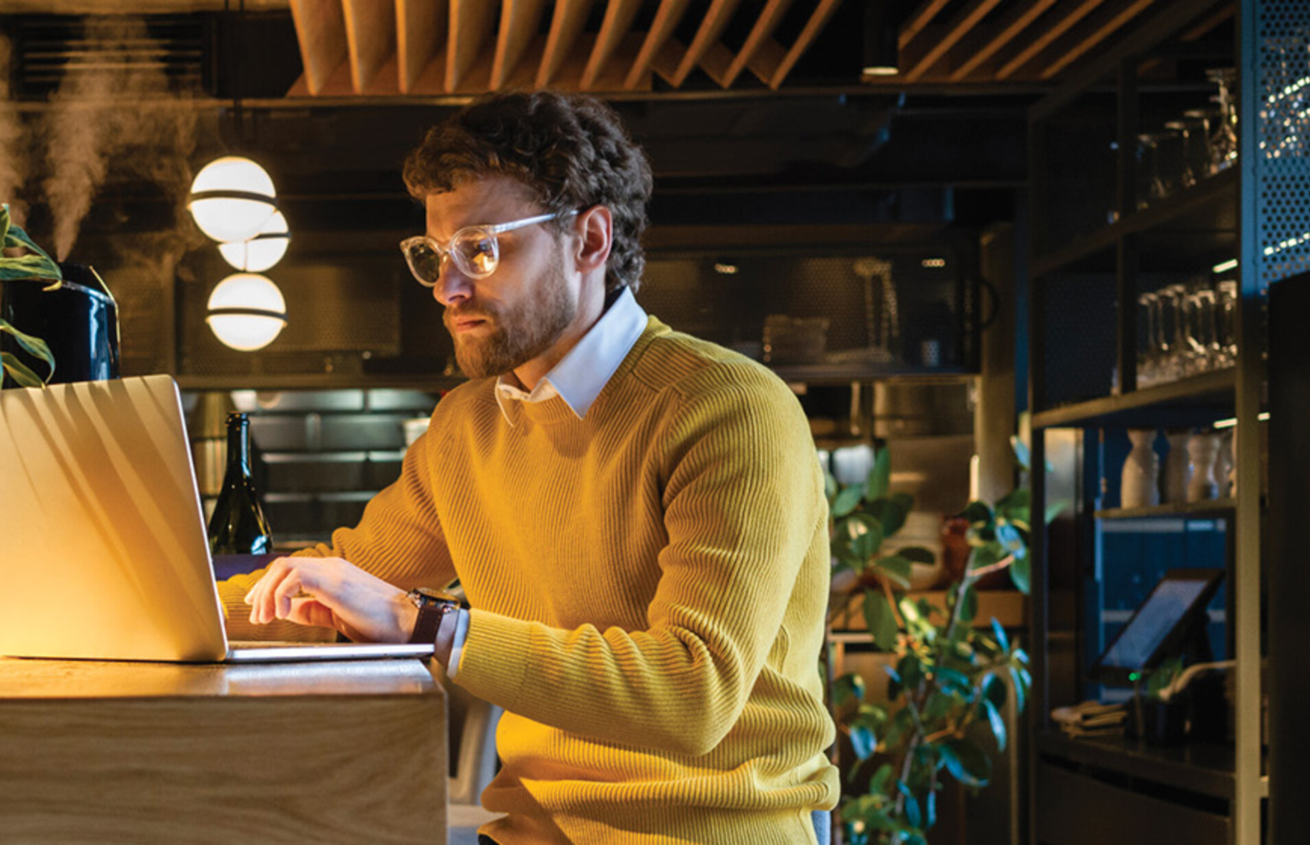 Businessman using laptop while sitting on seat at counter in cafe