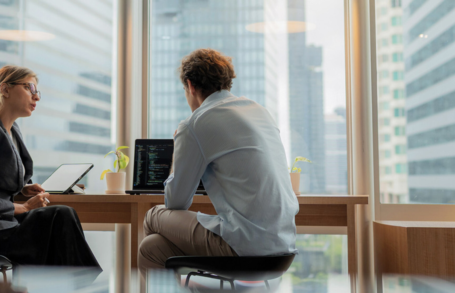 Adviser in modern office working on computer while speaking with clients