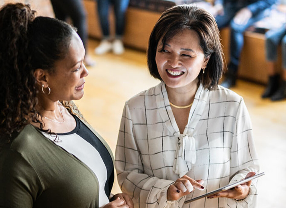 Two colleagues talking and using a digital tablet at work