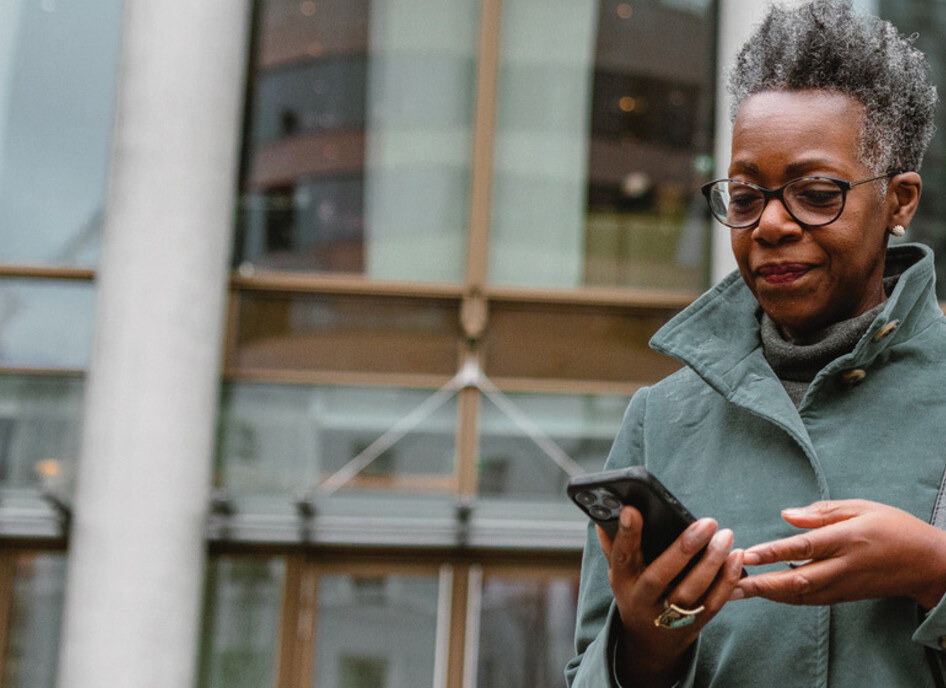 A woman on a smartphone in front of a sleek office building