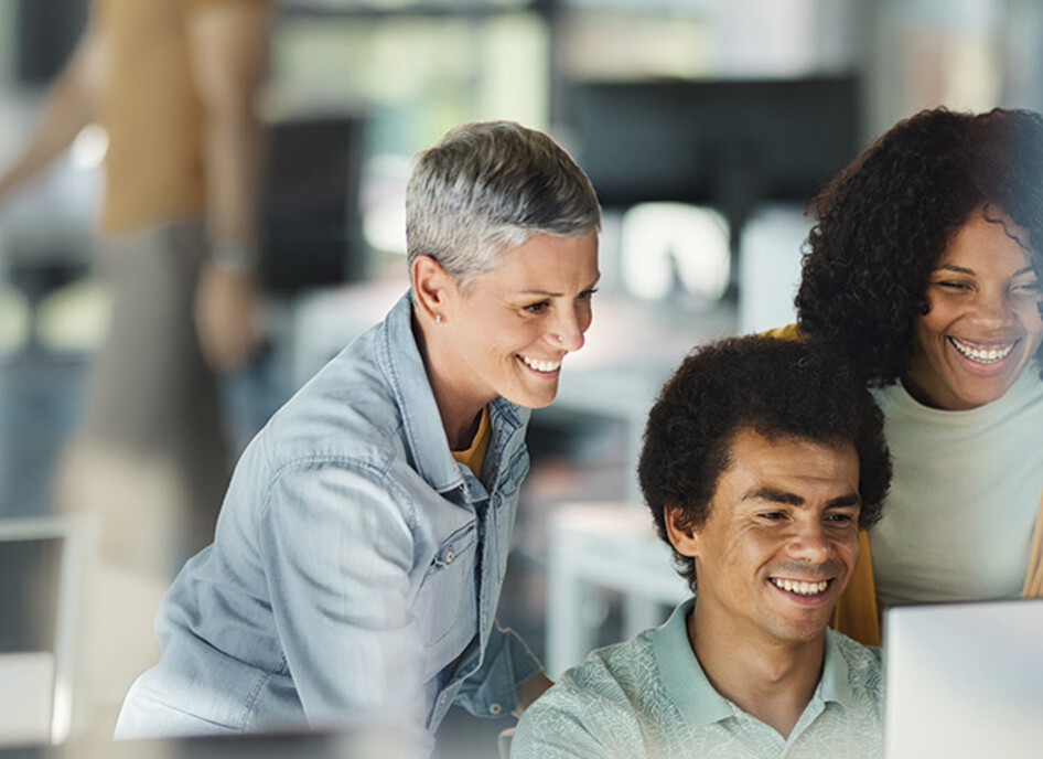 IT team smiles around computer