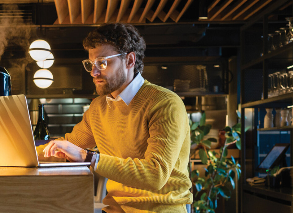 Businessman using laptop while sitting on seat at counter in cafe