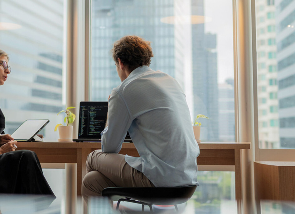 Adviser in modern office working on computer while speaking with clients