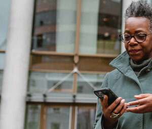 A woman on a smartphone in front of a sleek office building